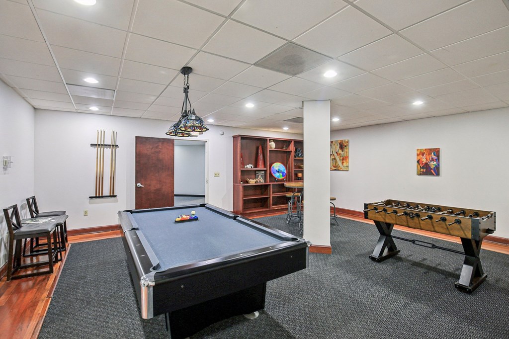A room with a pool table, a bench and a chair.