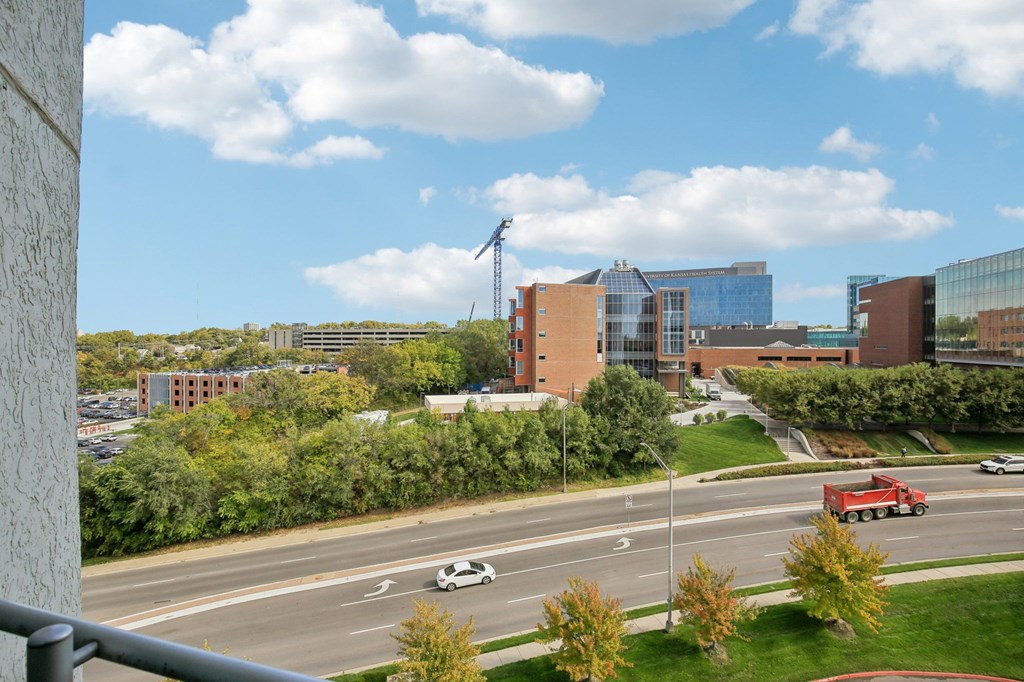 A view of a road with cars and a truck with buildings in the background.