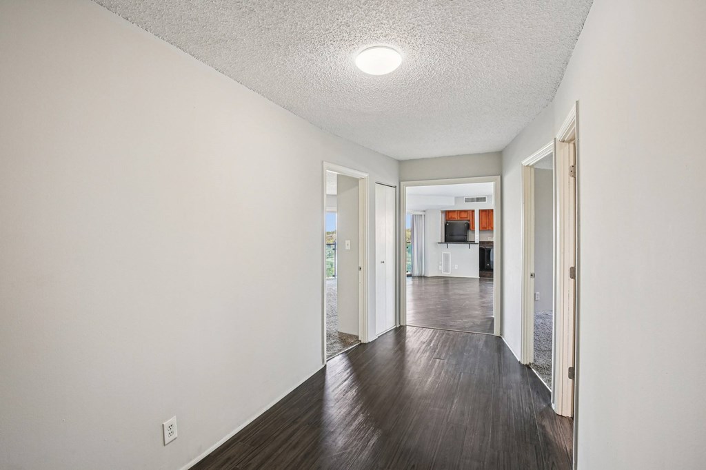 A long hallway with a white ceiling and wood flooring.