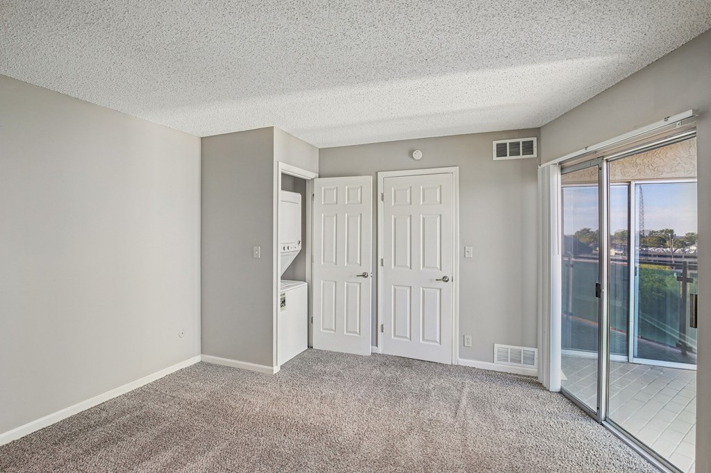 A room with a carpeted floor and a sliding glass door leading to a balcony.