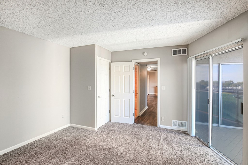 A room with a carpeted floor and a sliding glass door.