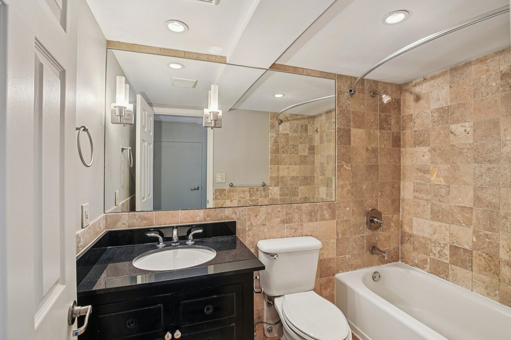 A bathroom with a black countertop and a white toilet.