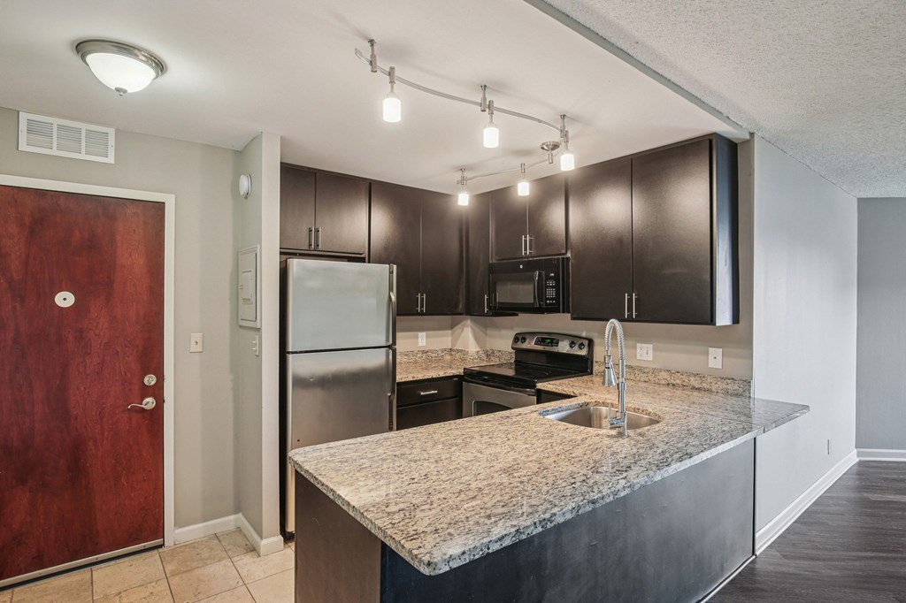 A kitchen with a granite countertop and stainless steel appliances.