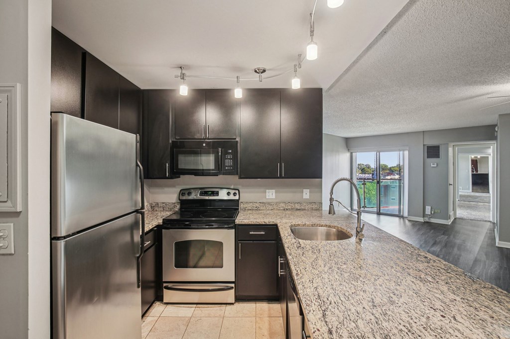 A kitchen with a stainless steel refrigerator, microwave, oven, and sink.