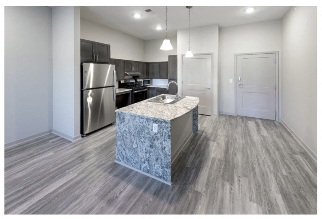 A kitchen with a marble island and stainless steel appliances.
