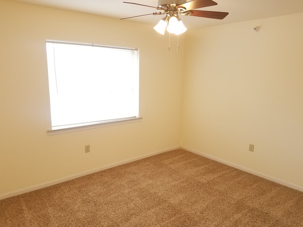 an empty room with a window and a ceiling fan