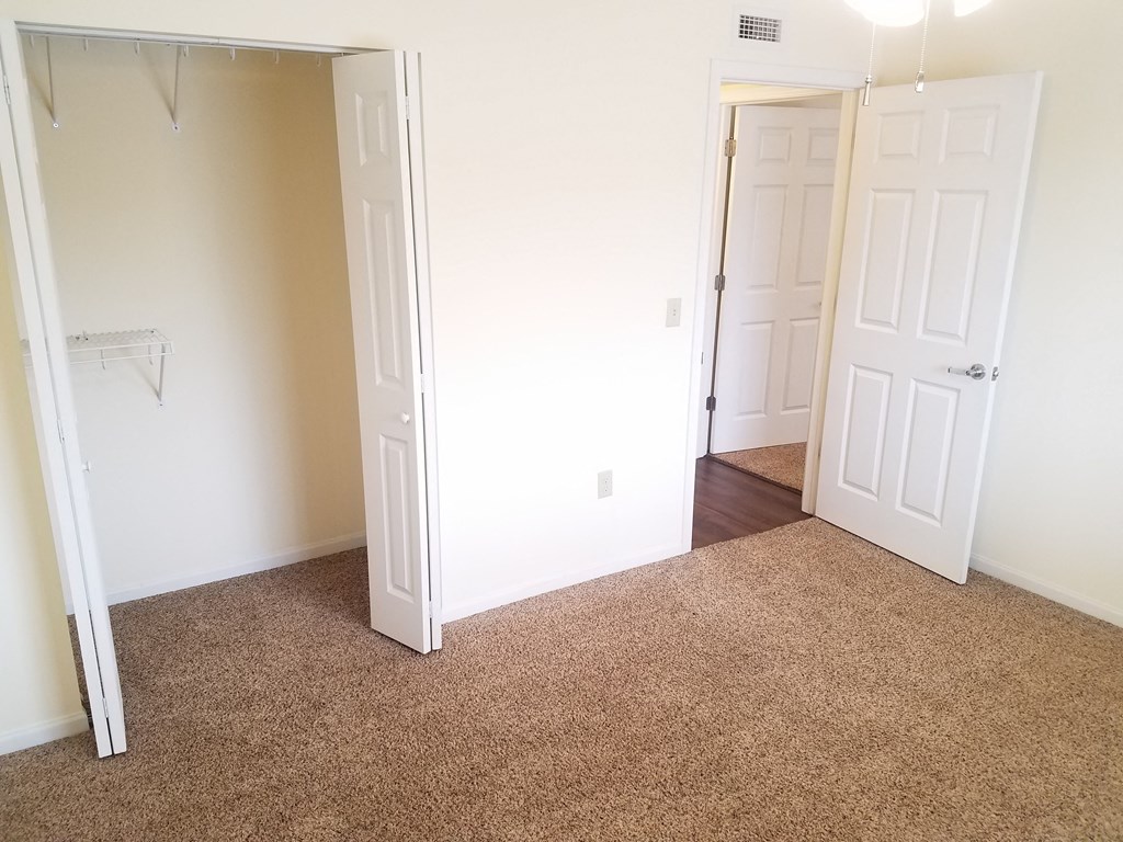 an empty bedroom with a carpeted floor and a closet