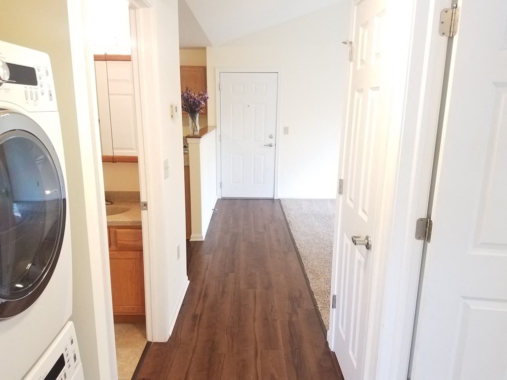 a hallway with a washer and dryer and a door to a kitchen