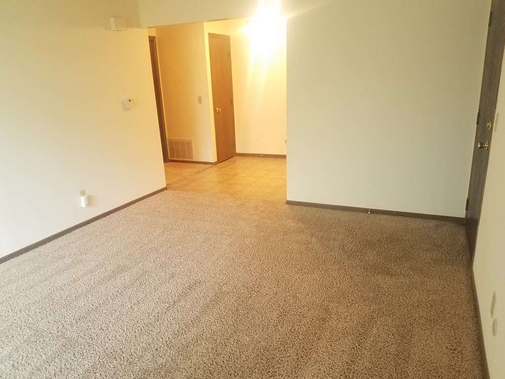 an empty living room with carpet and white walls