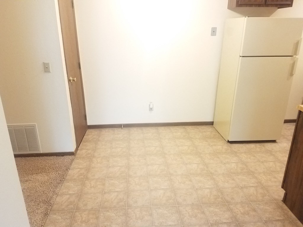 an empty kitchen with a refrigerator and a door