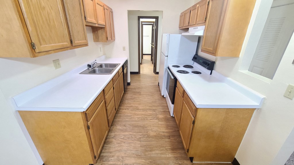 an empty kitchen with wooden cabinets and a white counter top