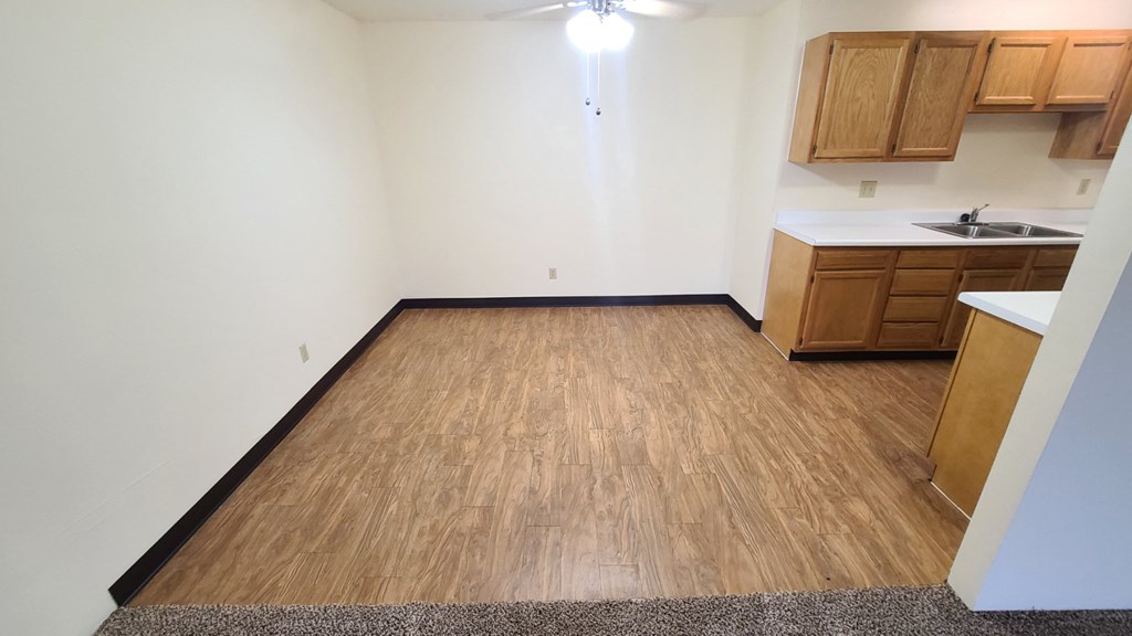 an empty living room with wood flooring in an empty apartment