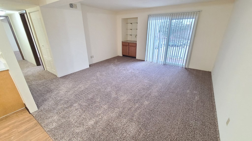 a living room with a carpeted floor and a window