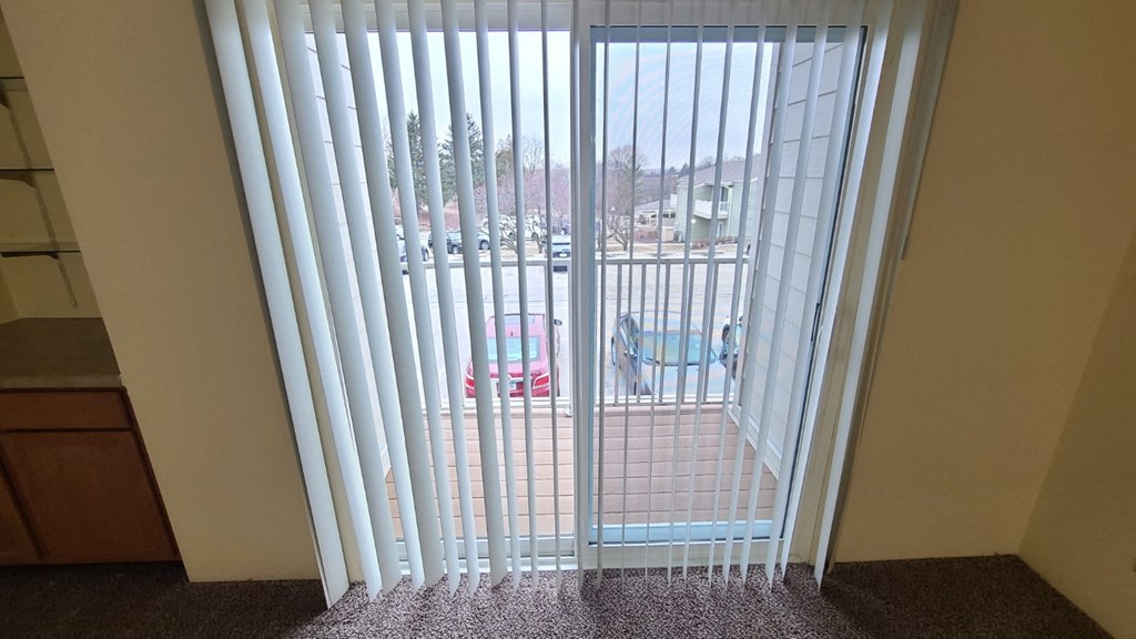 a sliding glass door with white vertical blinds in a room