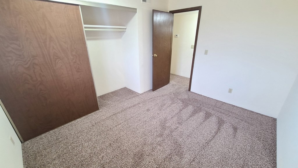 an empty room with two doors and a carpeted floor