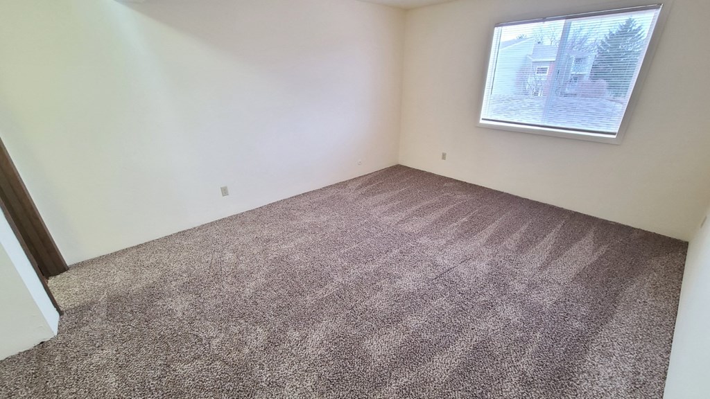 an empty room with carpet and a window