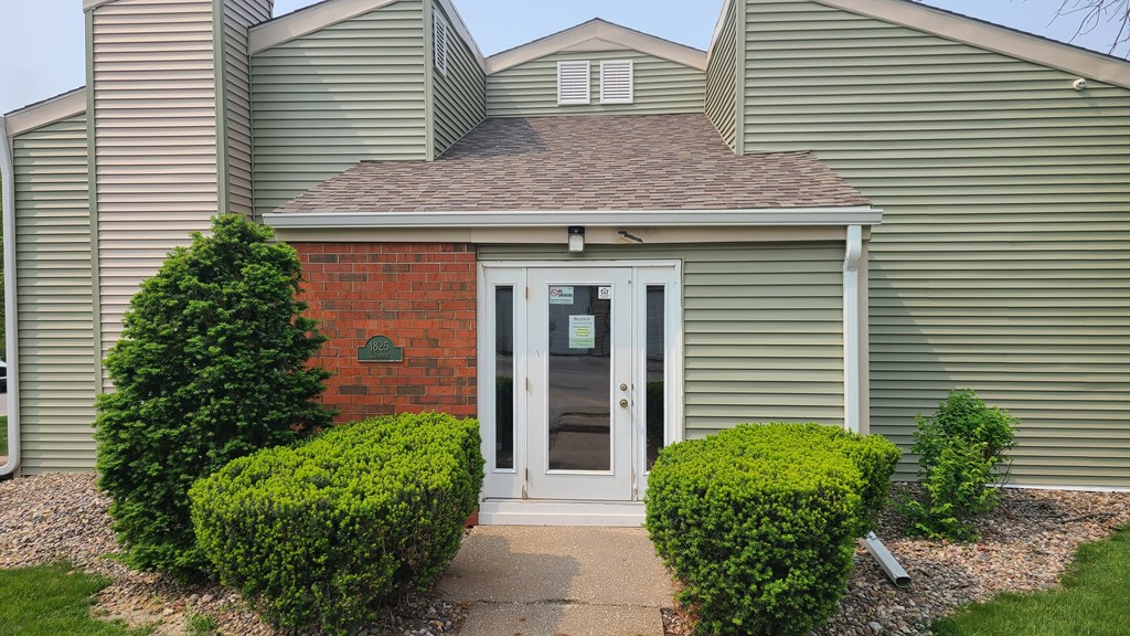 the front of a green house with a white door