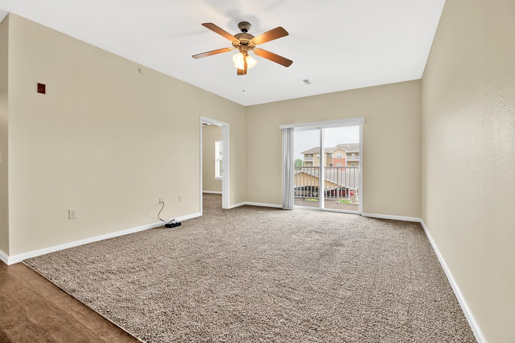 A room with a ceiling fan and carpeted floor.