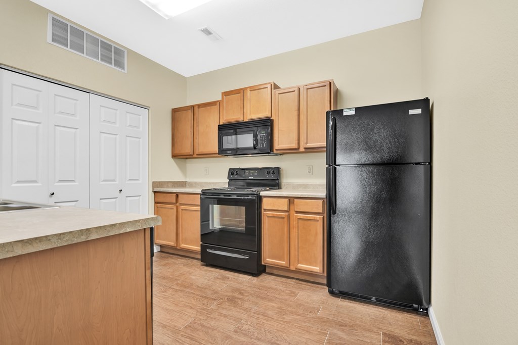 A kitchen with a black refrigerator, oven, and microwave.
