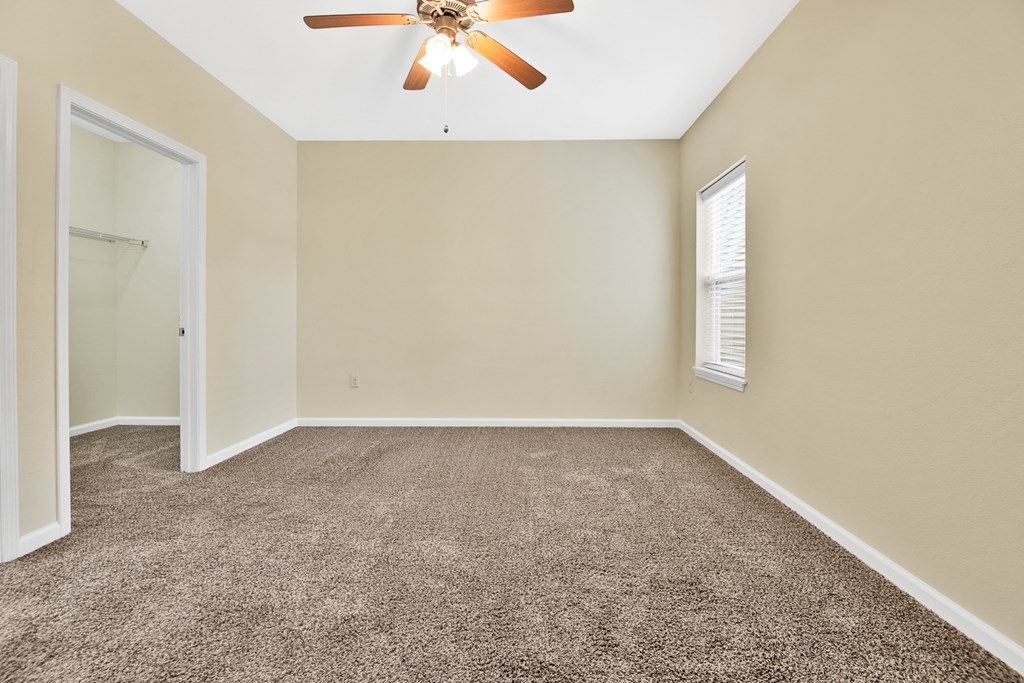 A room with a ceiling fan and carpeted floor.