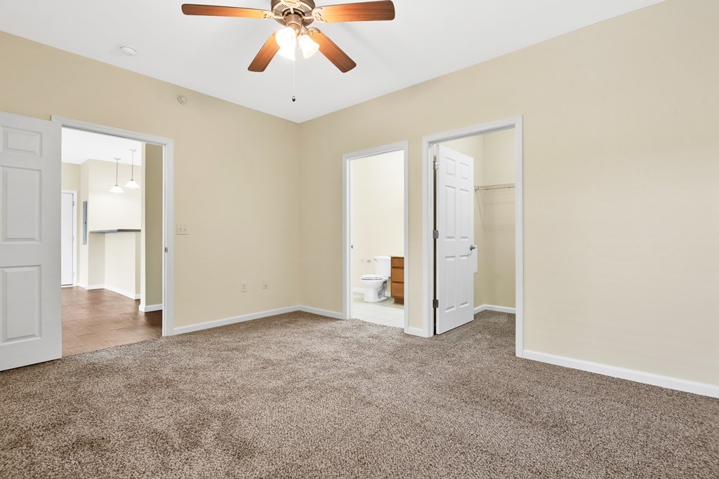 A room with a ceiling fan and carpeted floor.