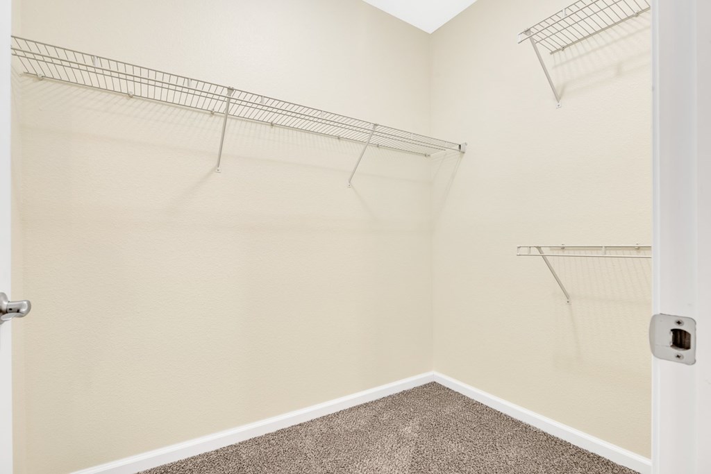 A white door is open to a room with a carpeted floor and two wire shelves.