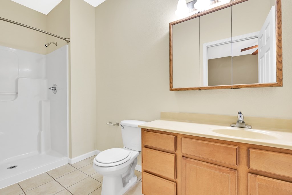 A bathroom with a toilet, sink, and mirror.