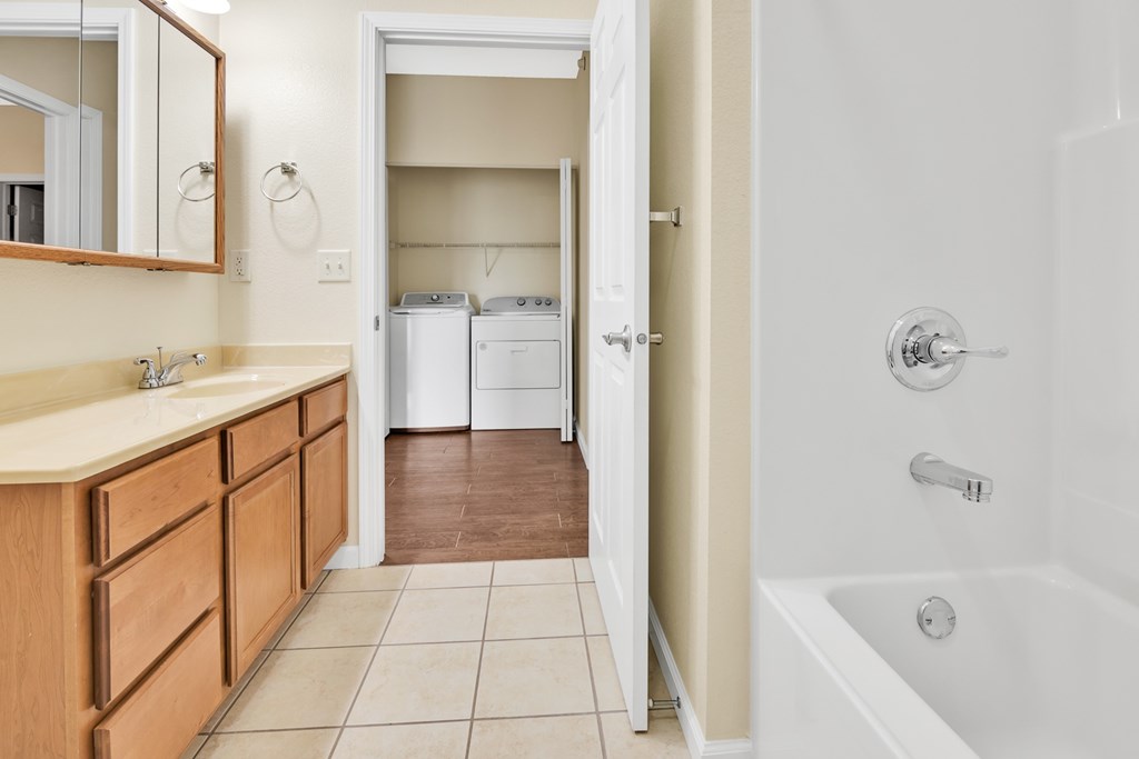 A bathroom with a white tub and a wooden vanity.