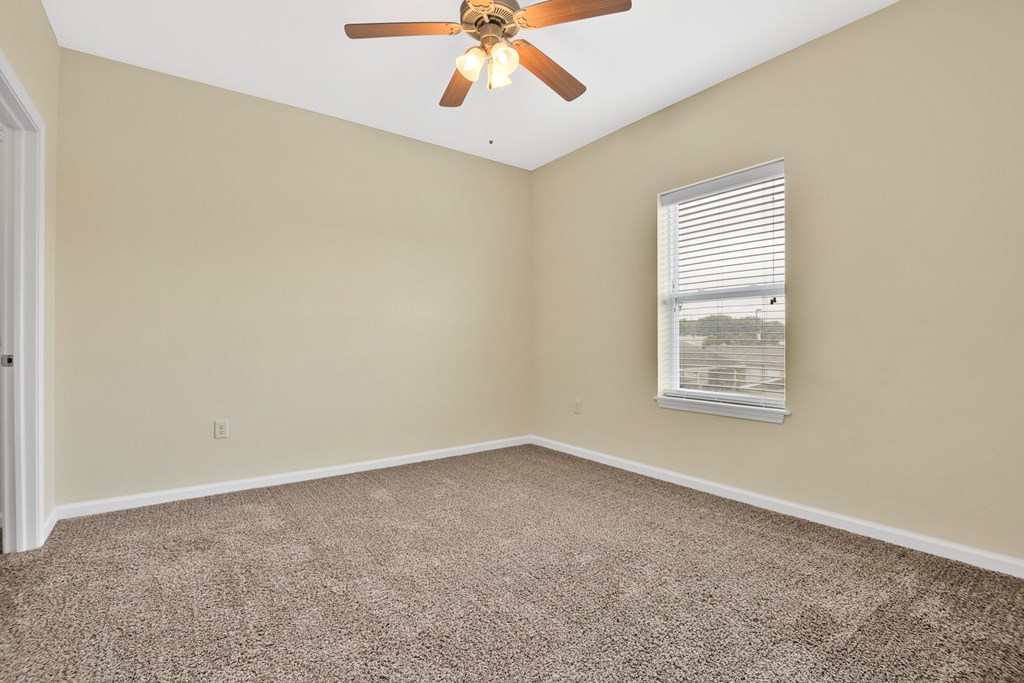 A room with a ceiling fan and a window with blinds.