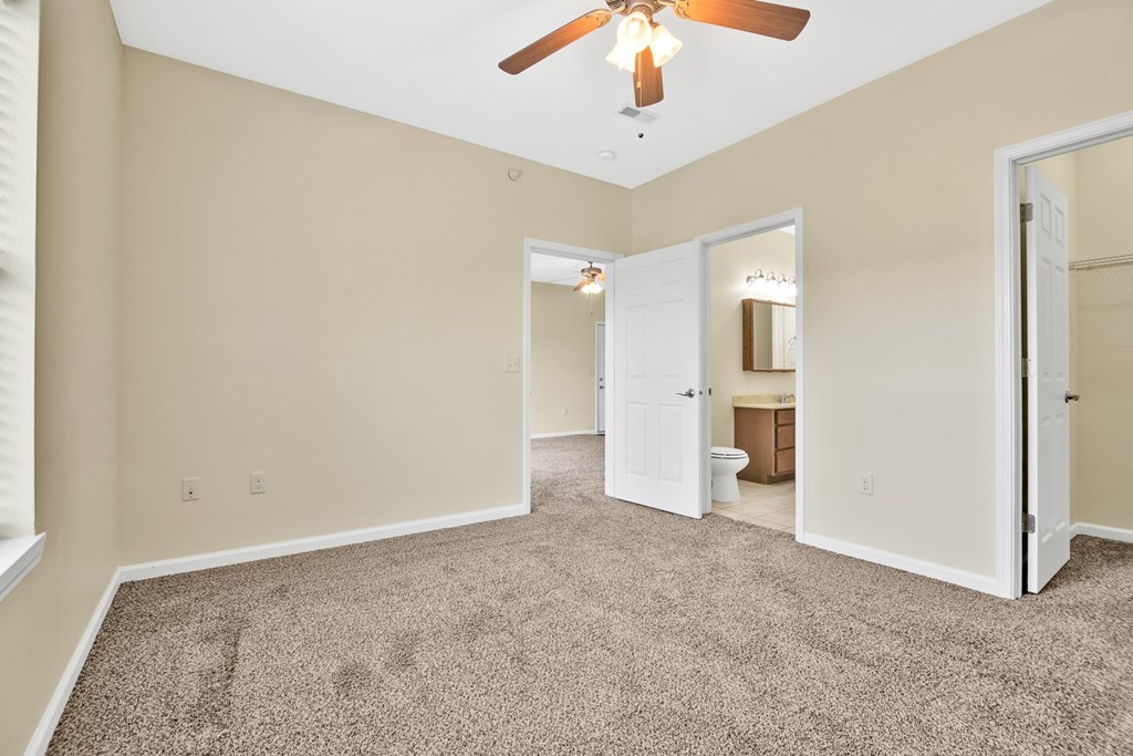 A room with a ceiling fan and carpeted floor.