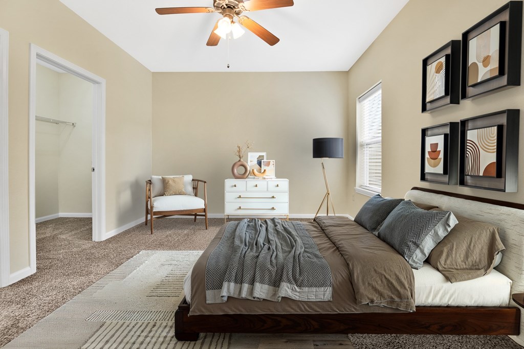 A bedroom with a bed, a chair, a dresser, and a ceiling fan.