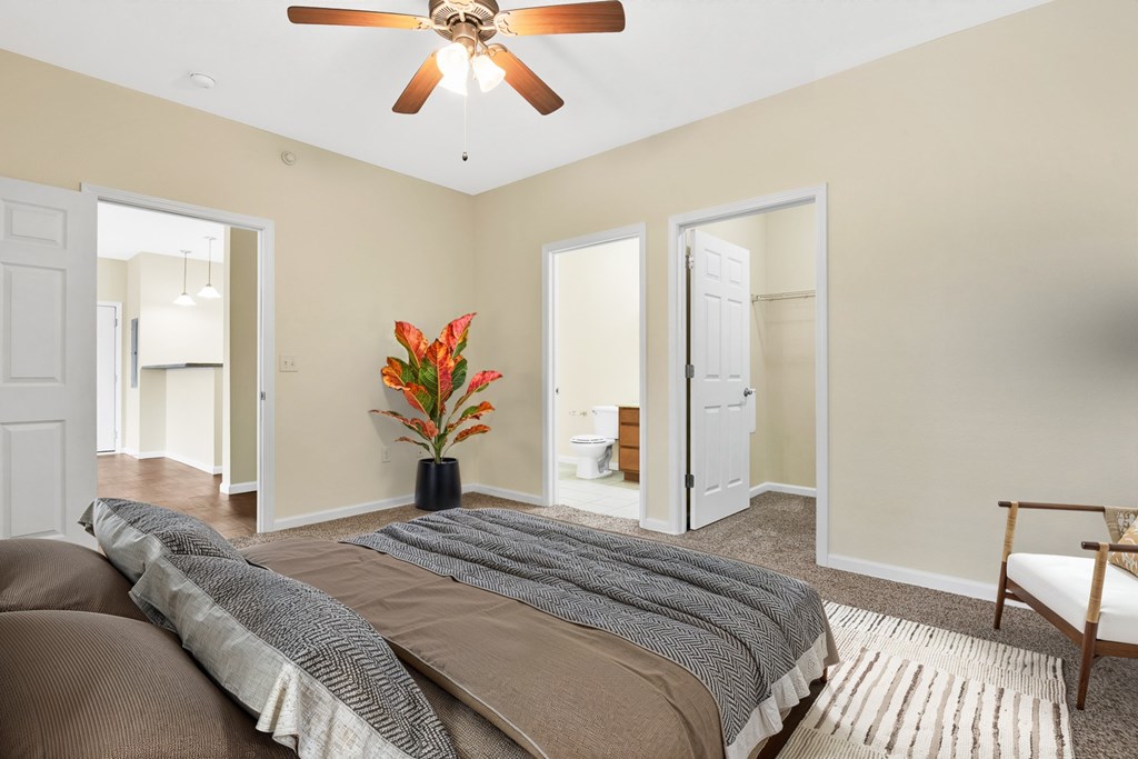 A bedroom with a bed, a ceiling fan, and a chair.