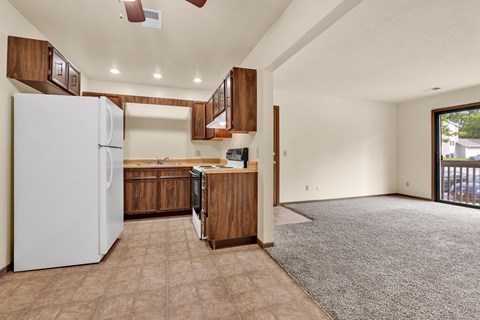 A kitchen with a white refrigerator and brown cabinets.
