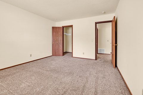 A room with a carpeted floor and two doors.