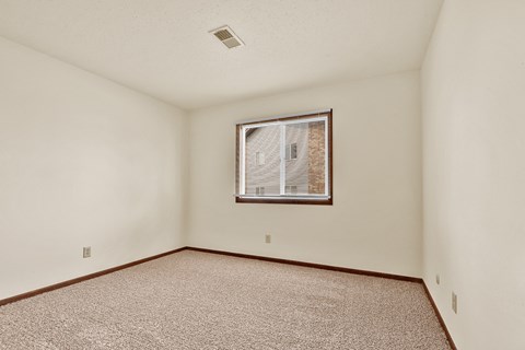 A room with a window and carpeted floor.