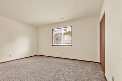A room with a carpeted floor and a window showing a view of a building outside.