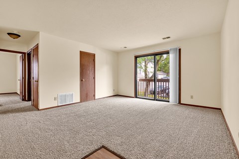 A room with a carpeted floor and a sliding glass door.