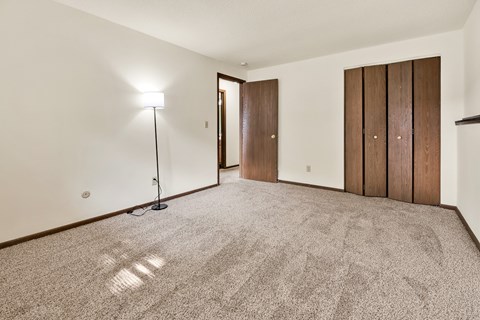 A room with a carpet floor and a lamp on the left side.