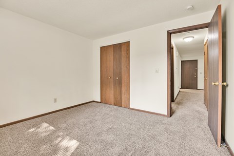 A room with a carpeted floor and a door on the right side.