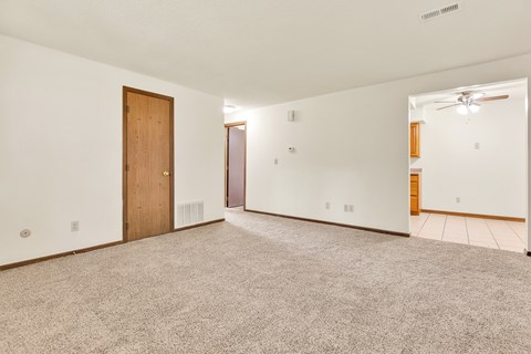 A room with a carpeted floor and a ceiling fan.