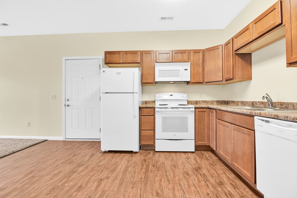 A kitchen with white appliances and wooden cabinets.