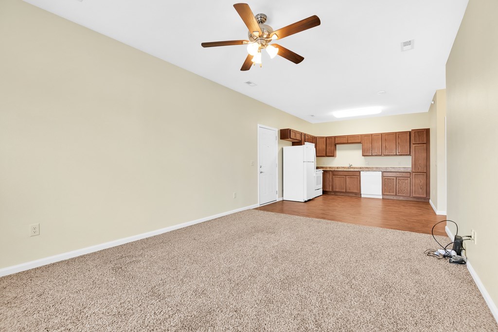 A room with a ceiling fan and carpeted floor.