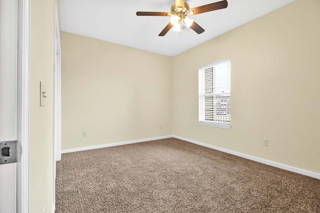 A room with a ceiling fan and carpeted floor.