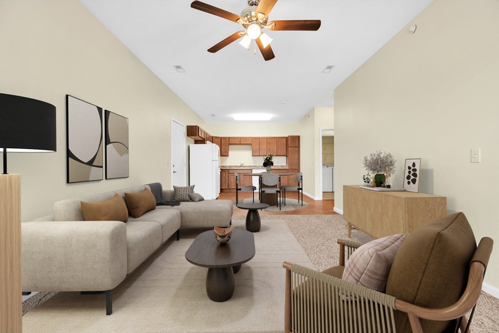 A living room with a beige couch, a brown chair, and a ceiling fan.