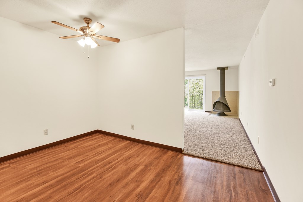 A room with a ceiling fan and wooden floors.