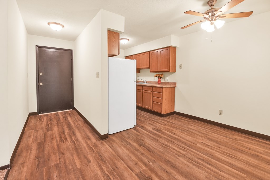 A room with a brown floor and a ceiling fan.