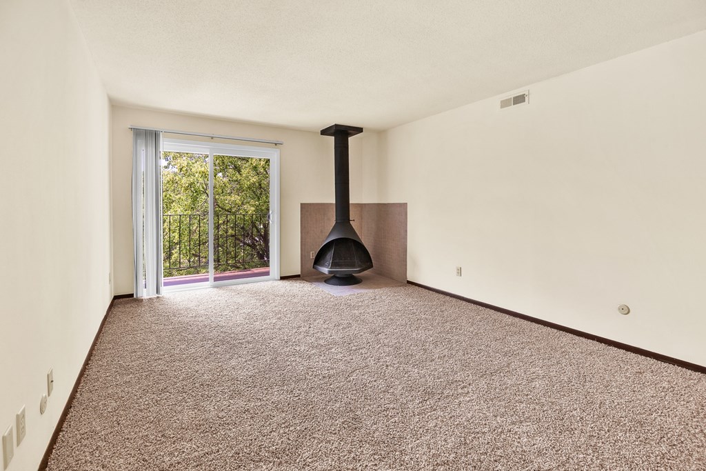 A room with a carpet floor and a fireplace.
