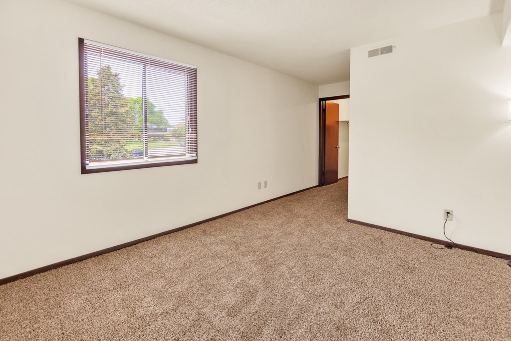 A room with a window and a carpeted floor.