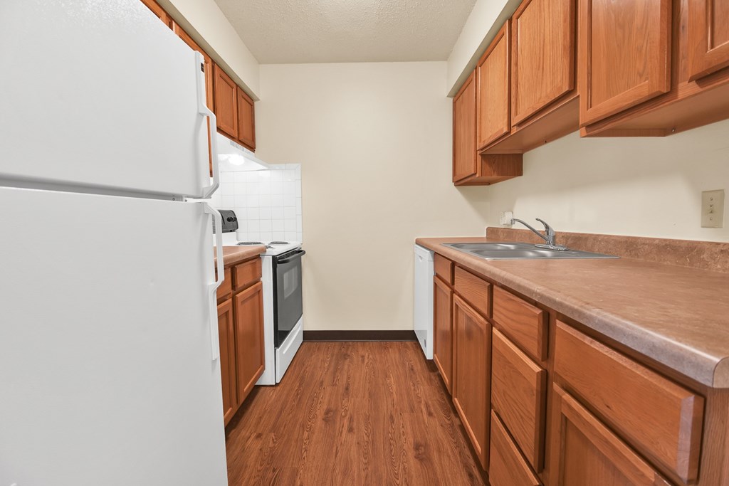 A kitchen with white appliances and wooden cabinets.