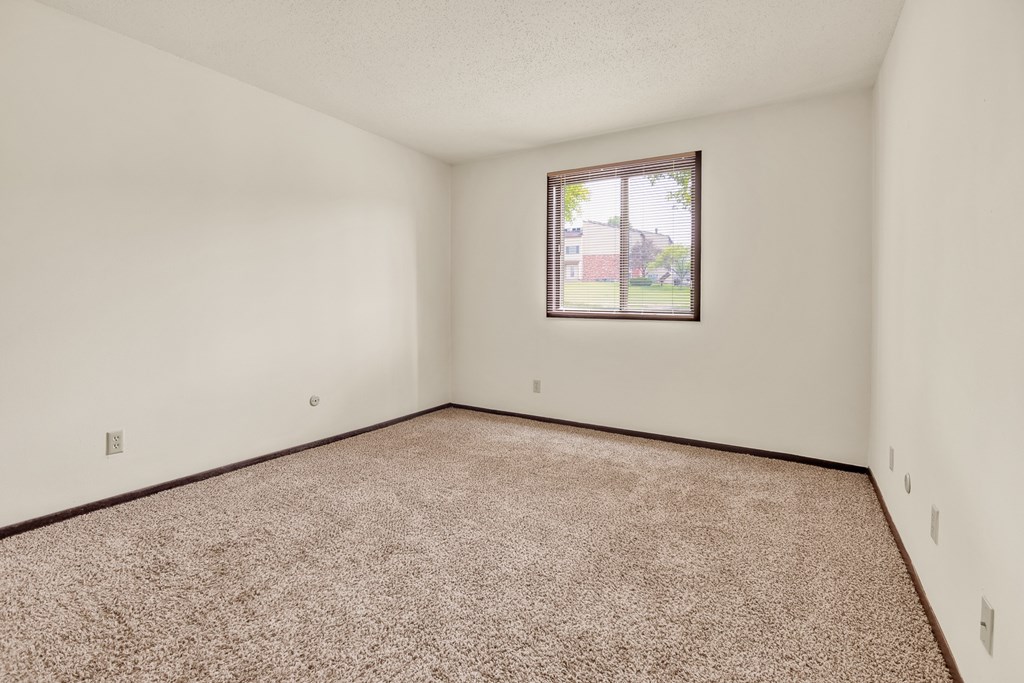 A room with a carpeted floor and a window.